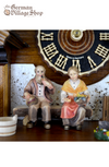 German Cuckoo Clock 8 day mechanical Hones chalet featuring black forest scene. Couple sitting on bench in front of chalet