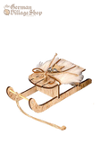 A large wooden snow sleigh with faux fur and silver bells. Attached is a string to hang the sleigh as a Christmas Tree Decoration.