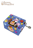 A rectangular music box with a silver hand crank extruding from the side. The box is deep blue with a cartoon scene of farm animals standing around a birthday cake. The text reads "Happy Birthday"