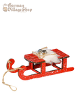 A large red snow sleigh with faux fur and silver bells. Attached is a string to hang the sleigh as a Christmas Tree Decoration.