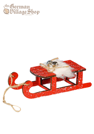 A large red snow sleigh with faux fur and silver bells. Attached is a string to hang the sleigh as a Christmas Tree Decoration.
