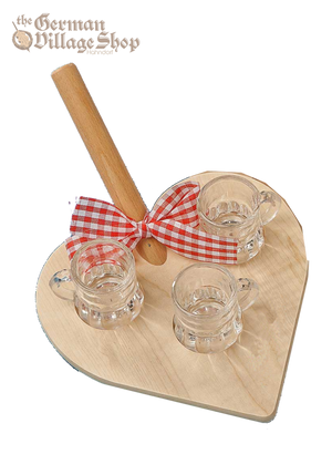 A light wood board in the shape of a love heart, with a handle. A red and white bow is tied around the handle, and 3 shot glasses are arranged on the board.