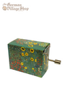 Rectangular music box with silver hand crank extruding from the side. The box is dark green with very small flowers, including sunflowers.