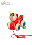 A bright red lady bug toy made from wood with large wheels. A string attached to the front allows a child to pull along the ground.