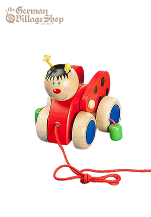 A bright red lady bug toy made from wood with large wheels. A string attached to the front allows a child to pull along the ground.