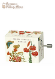 Rectangular music box with silver hand crank extruding from the side. The box is white with large flowers and butterflies. The text on the box says "Maria Sibylla Merian"